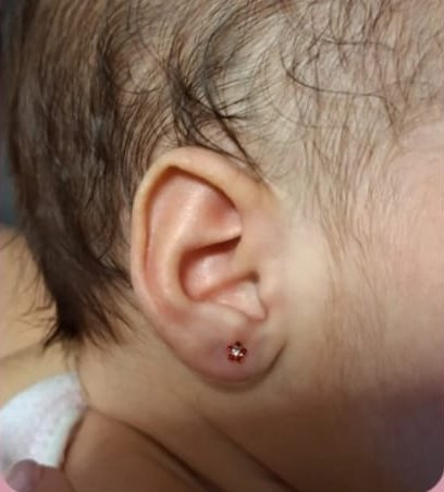 Brinquinho delicado na orelha da bebê